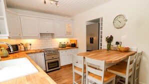 Une cuisine moderne avec des meubles blancs, un plan de travail en bois et un coin repas comprenant une table en bois et des chaises blanches.