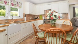 A kitchen with white cabinets, a round wooden table, and chairs with green cushions. - Applegarth (Scarborough)