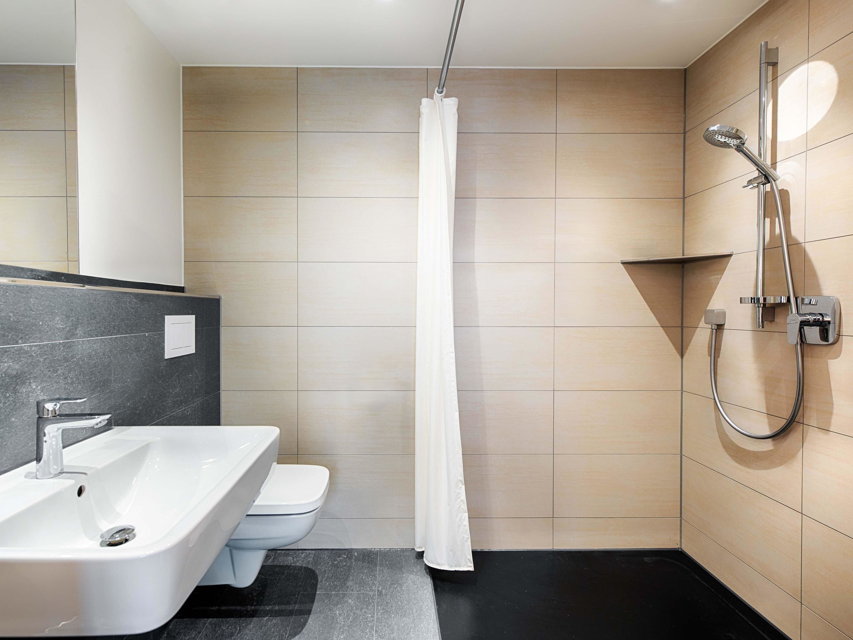 A modern bathroom with a shower, toilet, and sink.