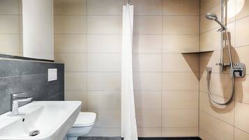 A modern bathroom with a shower, toilet, and sink.