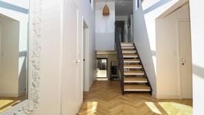 Een modern interieur met een houten trap, witte muren en een visgraatvloer.