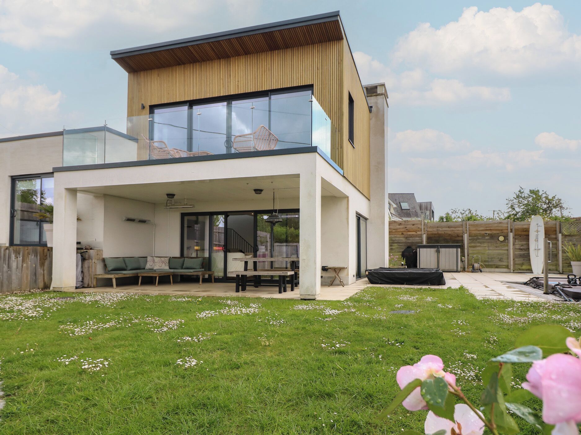 A modern two-story house with a covered patio, a visible staircase, and a fenced backyard.