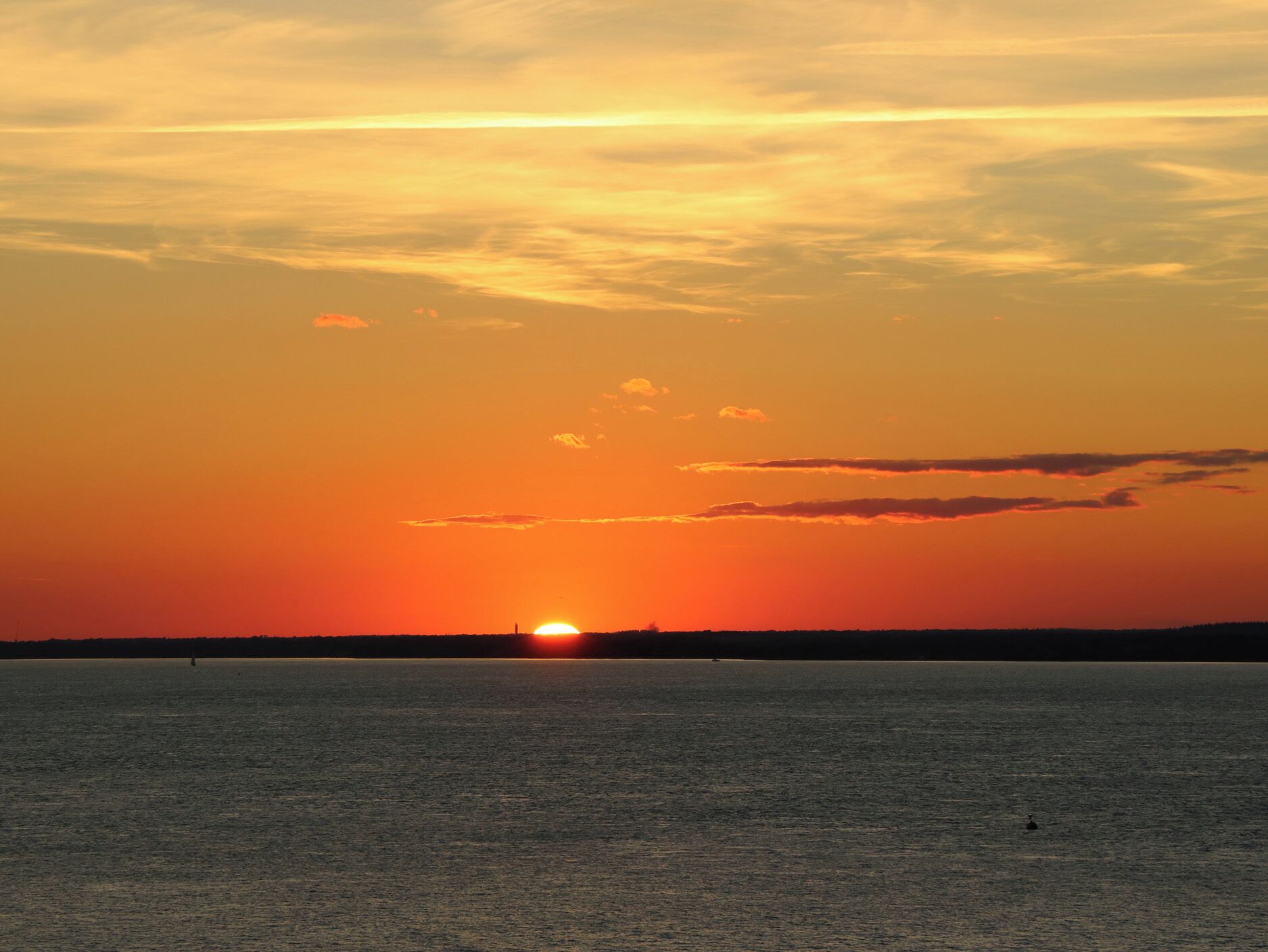 A sunset over a calm body of water with a clear horizon.
