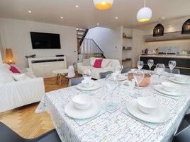 Una sala de estar moderna con comedor listo para una comida, una escalera y una cocina al fondo.