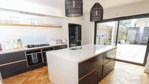 Een moderne keuken met een groot eiland, zwarte kastjes en een visgraatparketvloer.