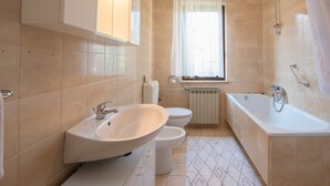 Et badeværelse med vask, toilet og badekar.