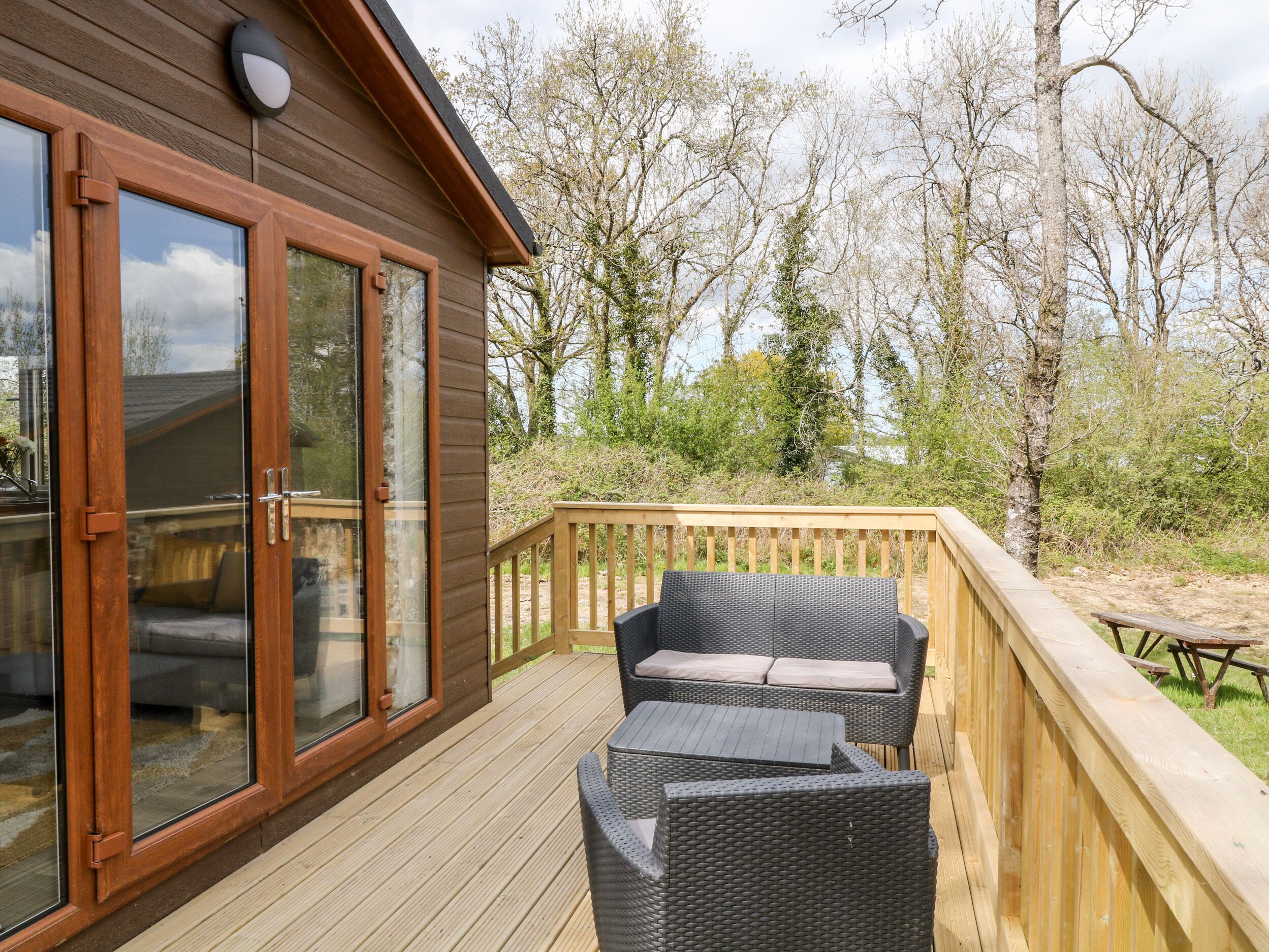 A wooden deck with wicker furniture and a glass door leading to a room.