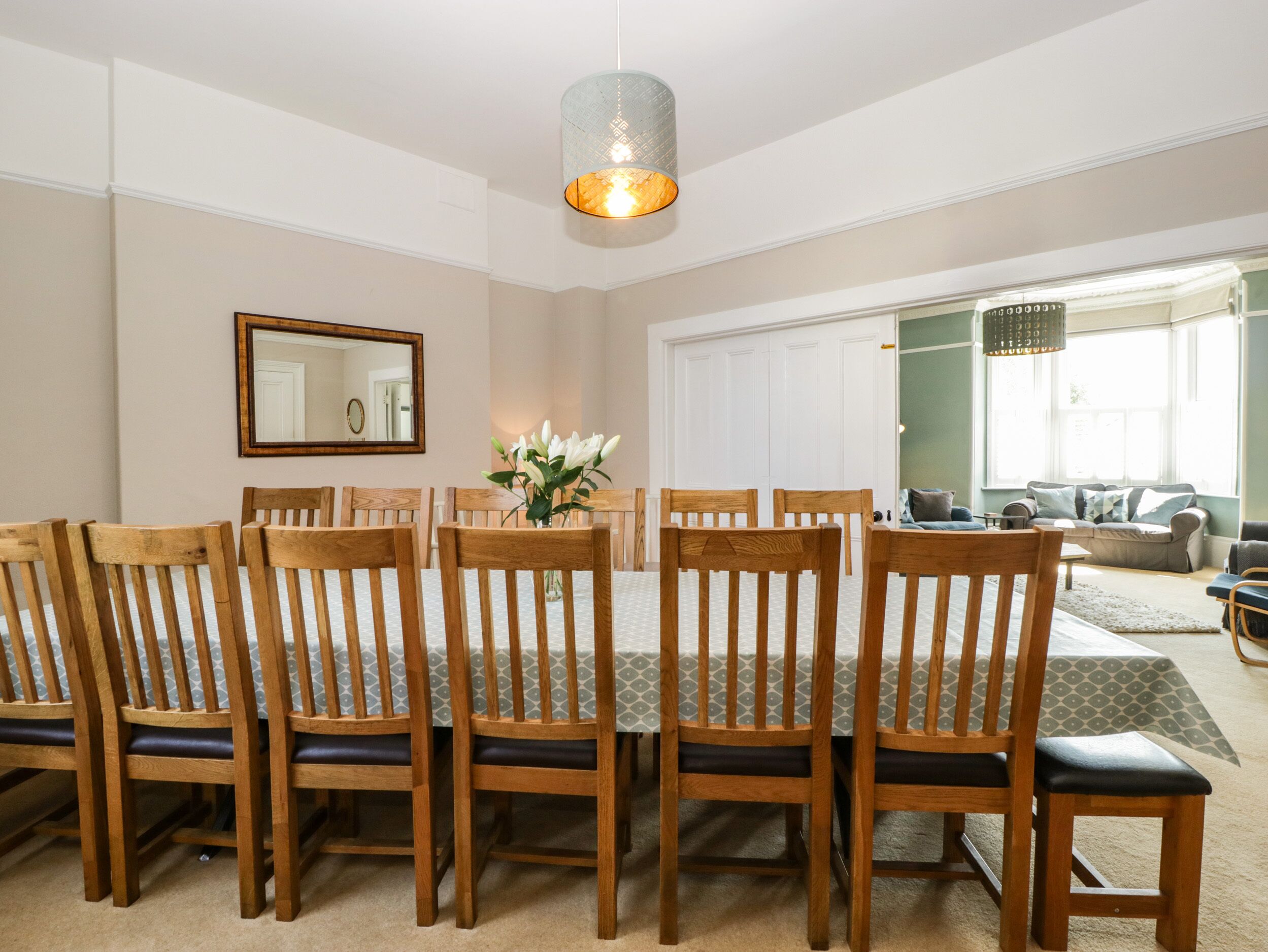 A dining area with a round table, wooden chairs, and a hanging light fixture.