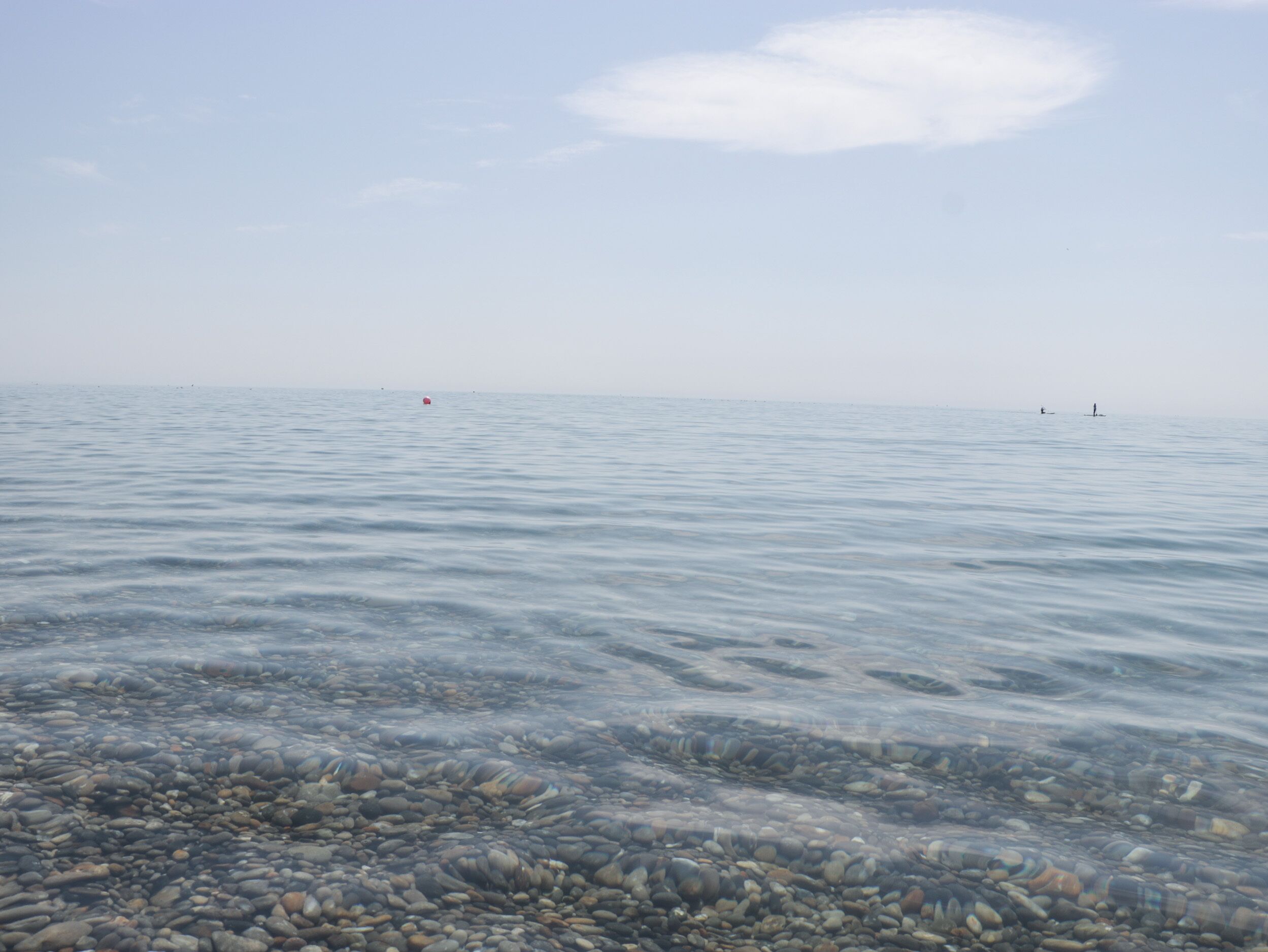 Mar tranquila con agua cristalina que deja ver un fondo pedregoso.