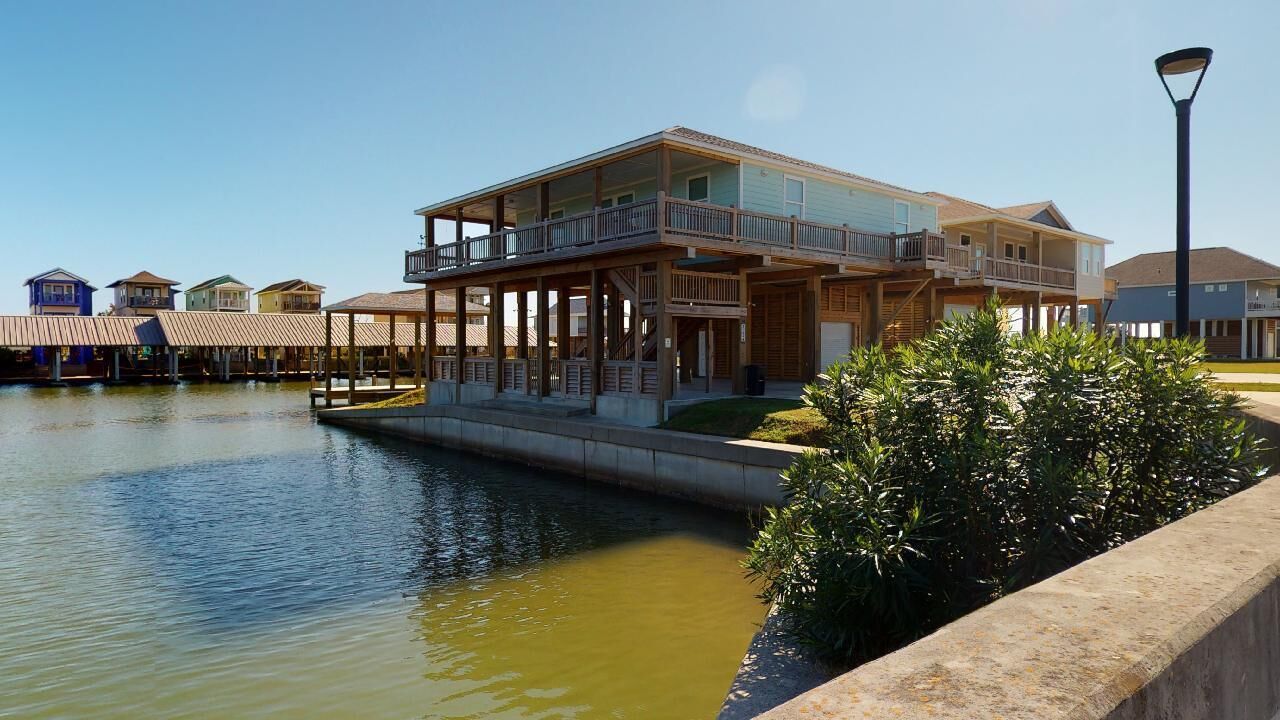 Ein Wohnhaus direkt am Wasser mit großem Balkon, überdachter Terrasse und Pool.