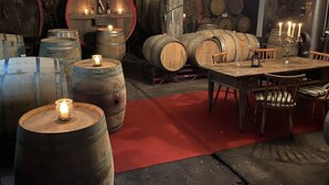 Een kelder met houten vaten, een eettafel, stoelen en een kroonluchter.