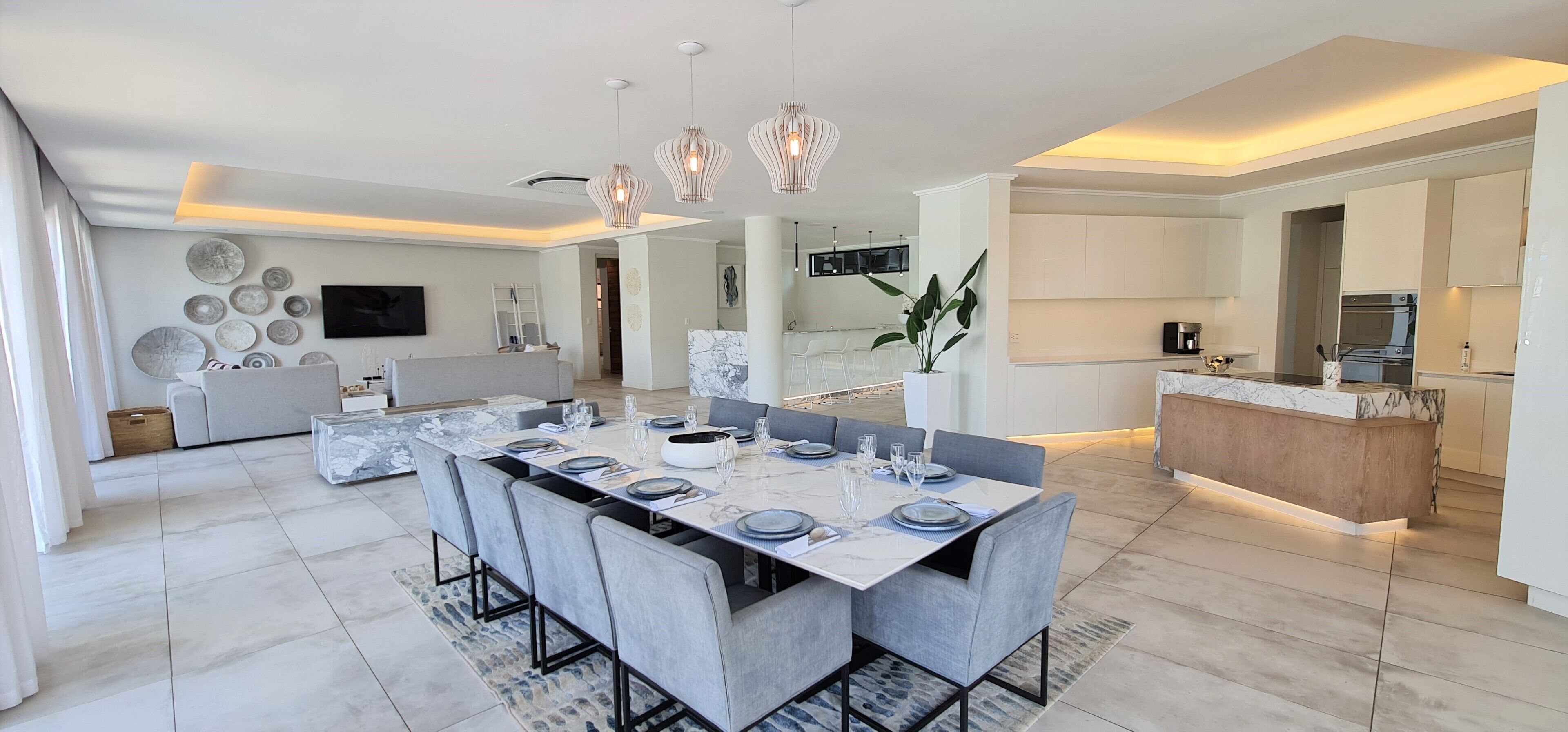 A modern kitchen with white cabinetry, a marble countertop, and a built-in oven.