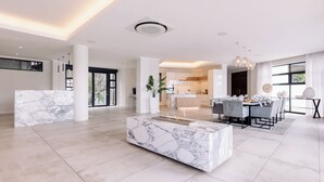 A spacious living area with a marble coffee table, a dining area with a set table, and a kitchen in the background. - MINT Resorts the Blyde (Pretoria)