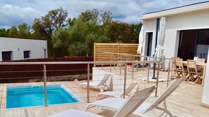 Un espace piscine aménagé sur le toit, avec des chaises longues et une petite piscine.
