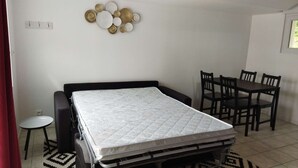 Ein gemütlicher Raum mit Bett, kleinem Tisch und Esstisch mit Stühlen.