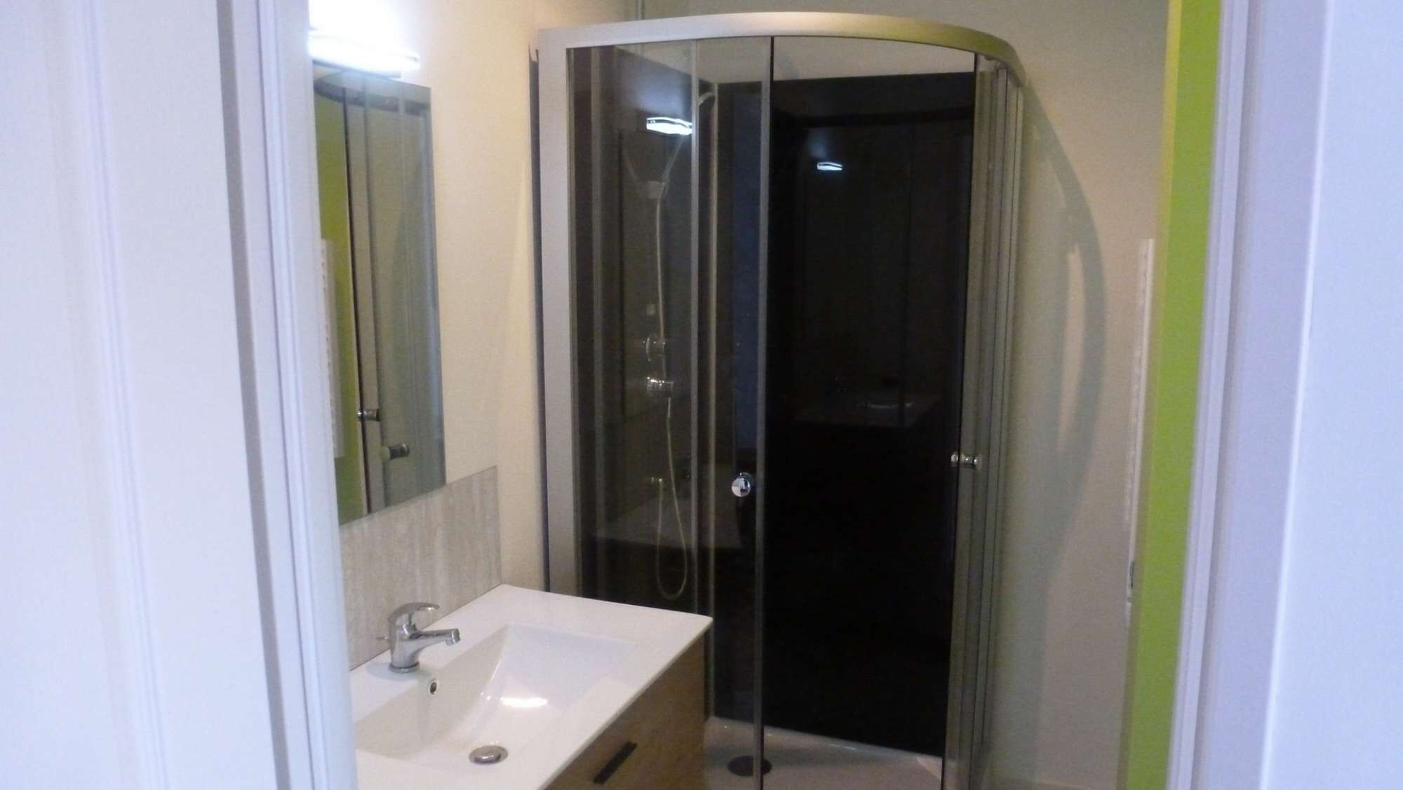 A bathroom with a white sink, a glass shower enclosure, and a mirror.