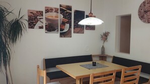 Ein Essbereich mit Holztisch, gepolstertem schwarzen Sitzbänken und einer hängenden Leuchte.