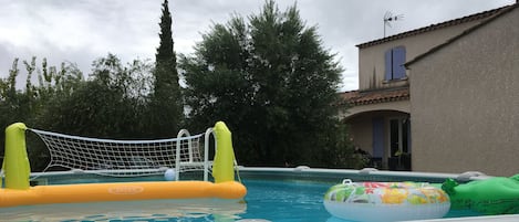 Una piscina al aire libre con estructuras de juego inflables y una red.