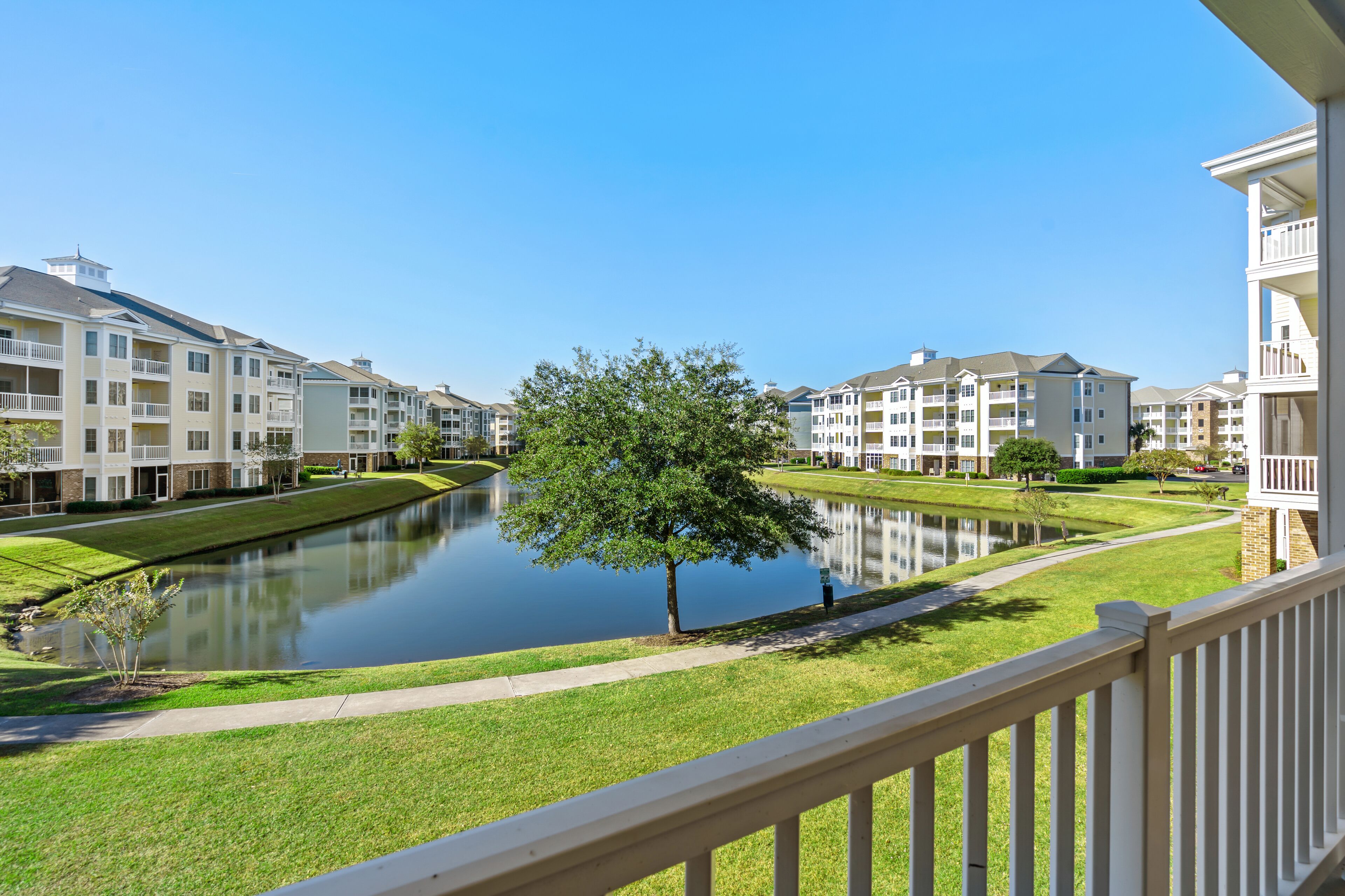 A residential area with apartment buildings, a central water feature, and a tree.