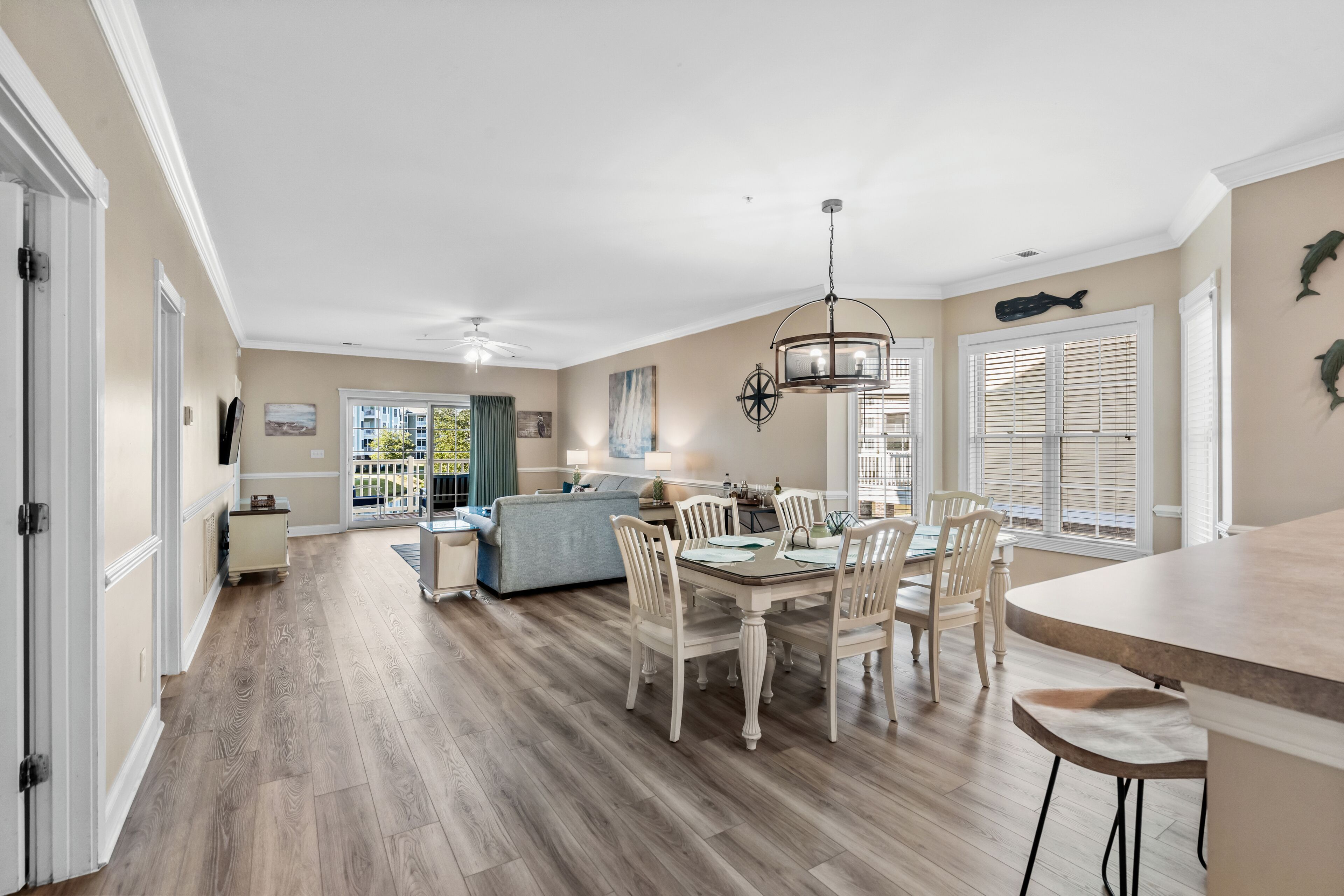 A spacious kitchen with a dining area, wooden flooring, and a view to the outside.
