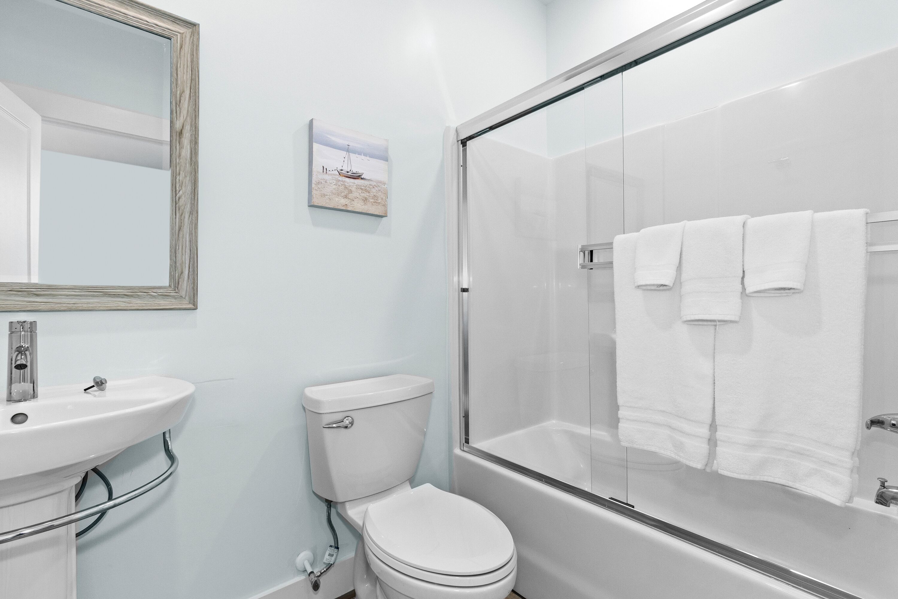 A bathroom with a white sink, toilet, and glass-enclosed shower.