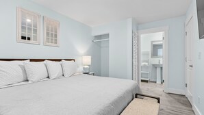 A bedroom with a large bed, a nightstand, a lamp, and a closet.