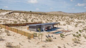 A modern house with a pool, surrounded by desert landscape.