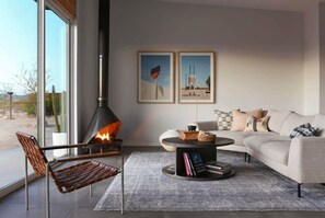 A modern living room with a fireplace, a sofa, a coffee table, and two framed pictures on the wall.