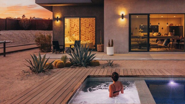 A modern house with a swimming pool, a patio, and a well-lit interior.