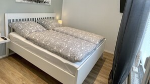 Quarto bem arrumado com cama, mesa de cabeceira e uma obra de arte na parede.