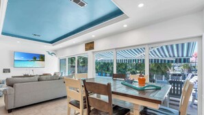 Uma sala de estar moderna com uma janela grande, uma mesa de jantar e um sofá.