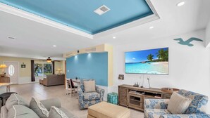 Uma sala de estar espaçosa com uma grande televisão de tela plana, assentos confortáveis e vista para o exterior.