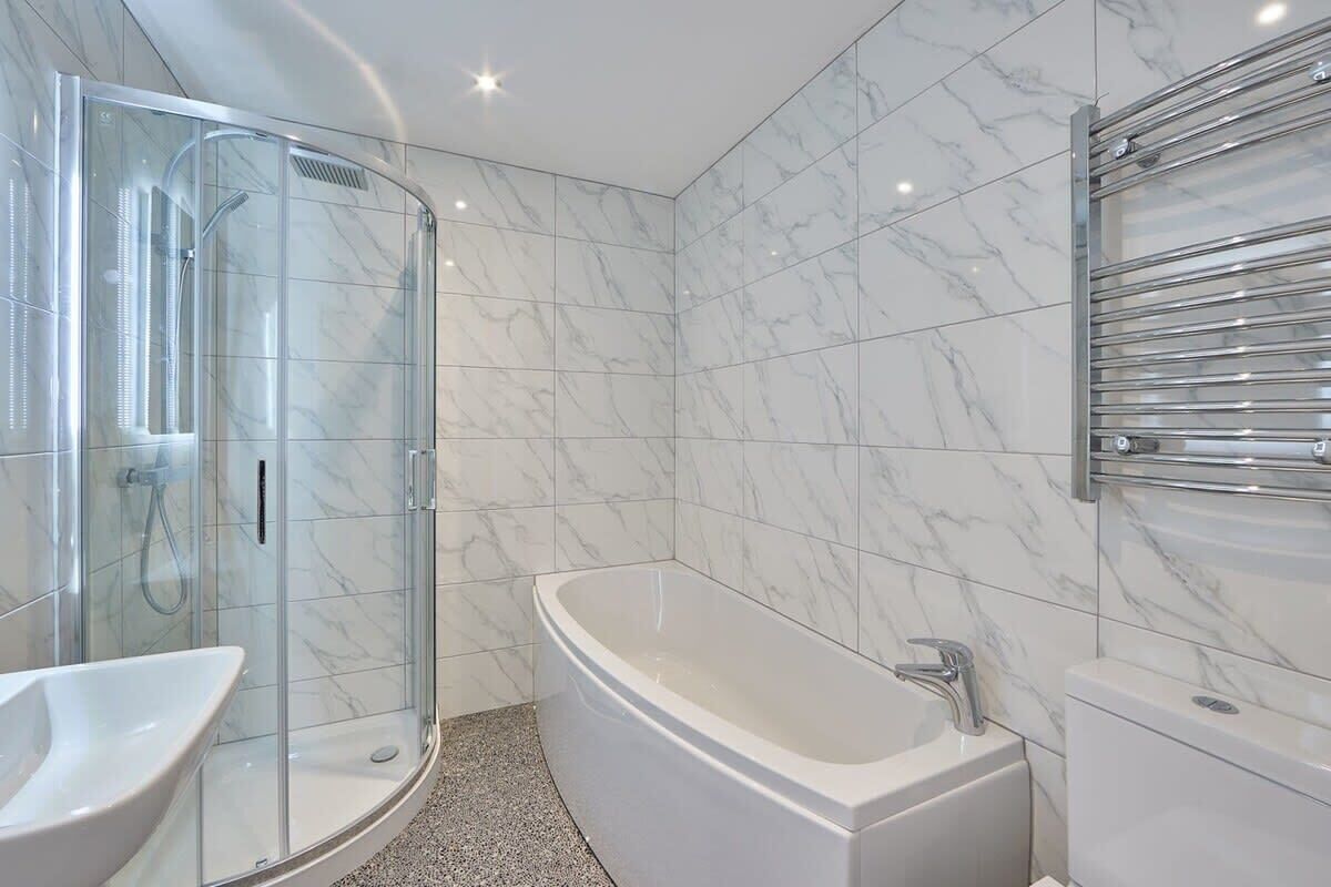 Un bagno moderno con doccia vetrata, vasca freestanding e lavabo.