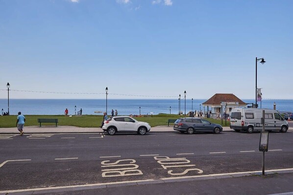 A coastal road with a bus stop and a white van parked on the side. - Host & Stay | Sand & Surf (Whitby)