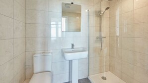 A modern bathroom with a toilet, sink, and shower.