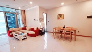 A modern living room with a sofa, coffee table, and dining table with chairs. - Spacious Modern 4-bed 140sqm Vinhomes Apartment (Ho Chi Minh City)