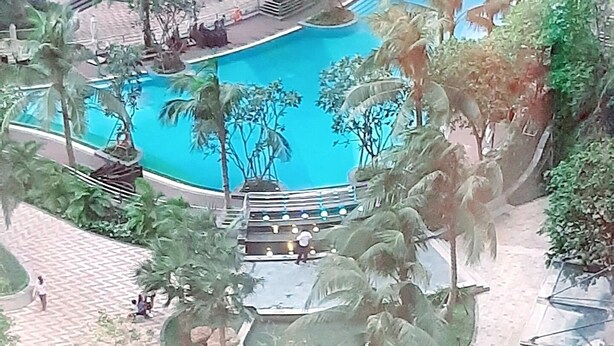 A swimming pool surrounded by palm trees and a brick pathway. - Spacious Modern 4-bed 140sqm Vinhomes Apartment (Ho Chi Minh City)