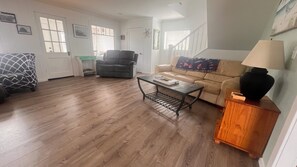 Una sala de estar con sofá, sillón, mesa de centro y lámpara.