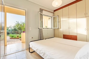 Un dormitorio con cama, armario y ventana con cortinas.