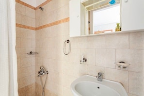 Un baño con ducha, lavabo y espejo.