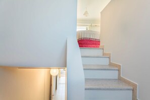 A staircase with white walls and a red carpeted landing.