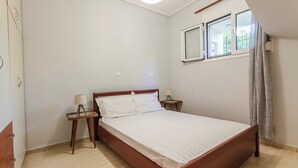 Un dormitorio con una cama individual, una mesita de noche, una lámpara y una ventana con cortinas.