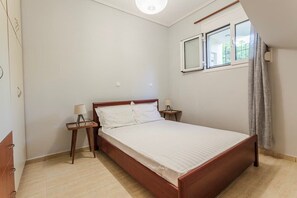 Un dormitorio con una cama individual, una mesita de noche, una lámpara y una ventana con cortinas.