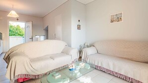 A room with two beige sofas, a glass coffee table, and a door leading outside.