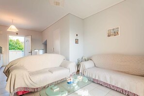 A room with two beige sofas, a glass coffee table, and a door leading outside.