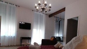 Ett hotellrum med en stor säng, en kristallkrona, en platt-TV och en spegel.