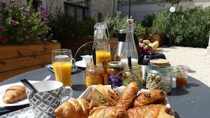 A breakfast setup with croissants, juice, and various condiments on an outdoor table. - La Romantique, luxury suite with bathtub at Château La Vidalle (Vendres)