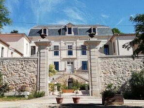 A historic building with a symmetrical facade, stone walls, and a central entrance with a staircase.