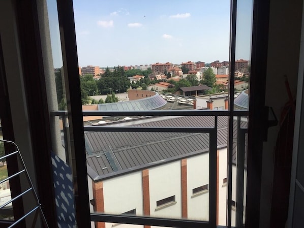 A view through a window of a building with multiple floors, featuring a mix of residential and commercial buildings in the background.