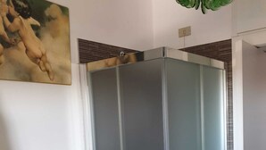 A modern bathroom with a glass shower enclosure, a towel rack, and a painting on the wall. - appartamento luminoso  con balcone, silenzioso davanti a un parco vicino a GYM (Gallarate)